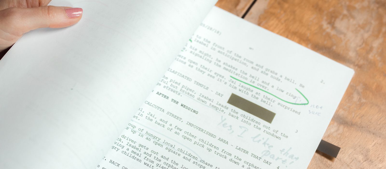 Printed manuscript pages with handwritten editorial corrections spread across a wooden desk