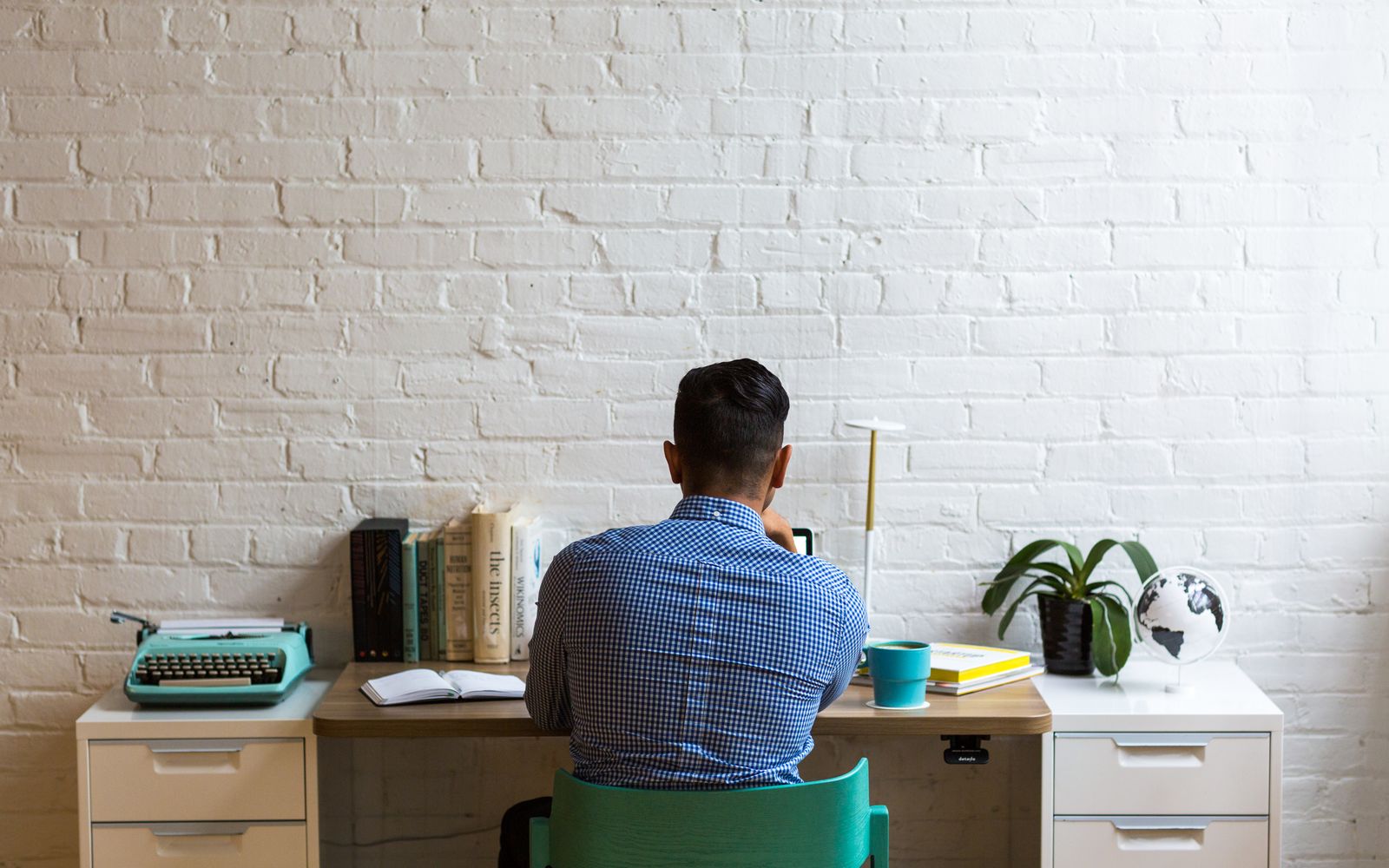A writer working at a bright home-office desk with a typewriter, reference books and notebooks