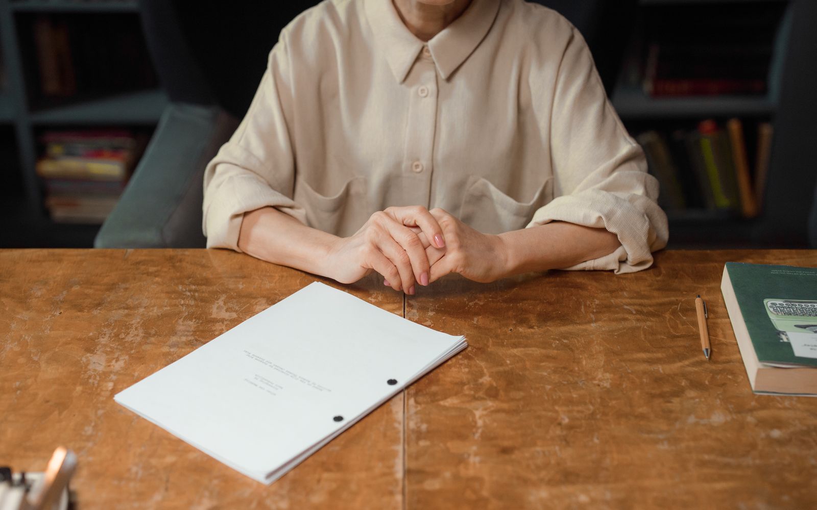 An editor reviewing an annotated manuscript at a wooden table in a book-lined office